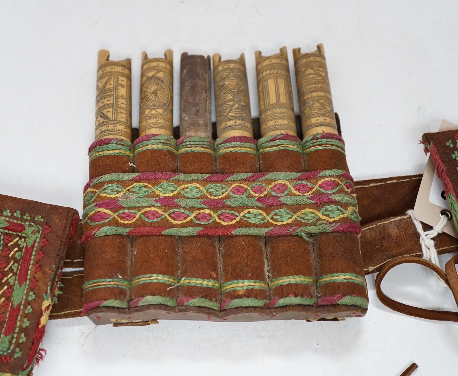 A 19th century Armenian gazyr belt, with decorative silk embroidery on suede and carved bamboo shot and gunpowder containers, 68cm long. Condition - slightly worn from use
